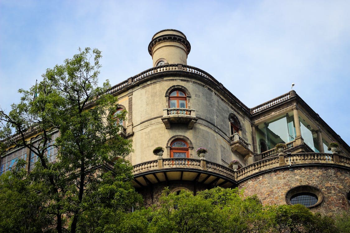 El Castillo de Chapultepec rodeado de árboles frondosos se alza sobre una colina en la Ciudad de México